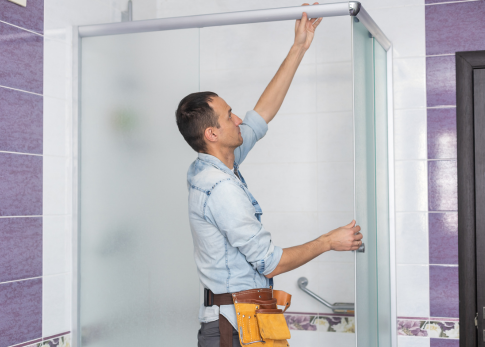 Expert installing frameless glass shower enclosure